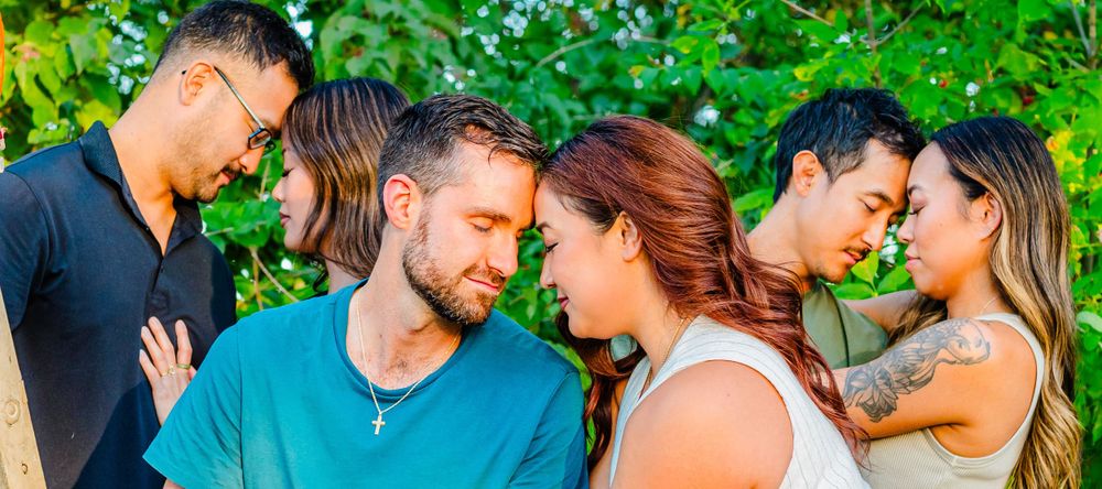Couples share intimate moments together against lush green foliage background.
