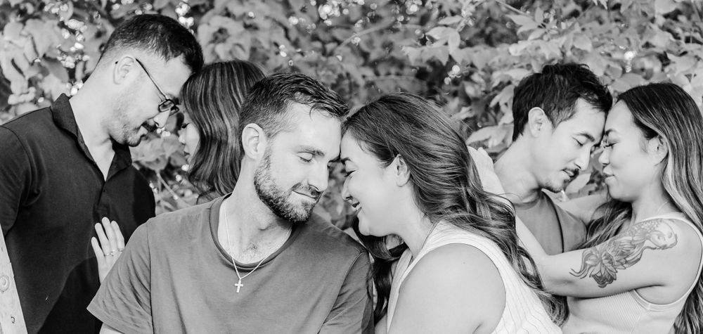 Black and white candid photo of three happy couples sharing intimate moments together outdoors.