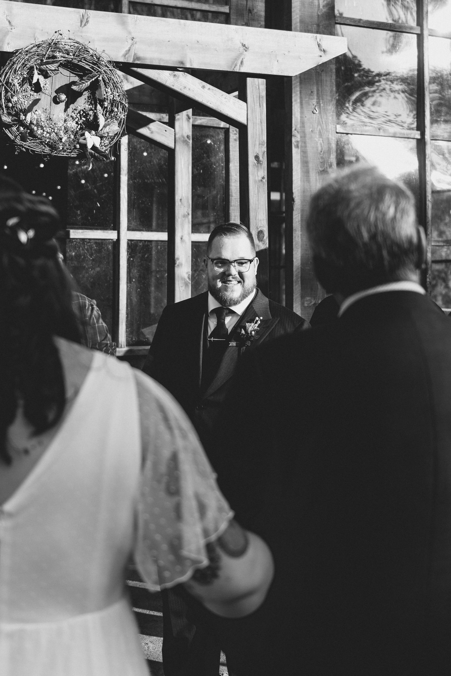 A black and white photo of a joyful wedding scene with guests gathered at a doorway entrance.