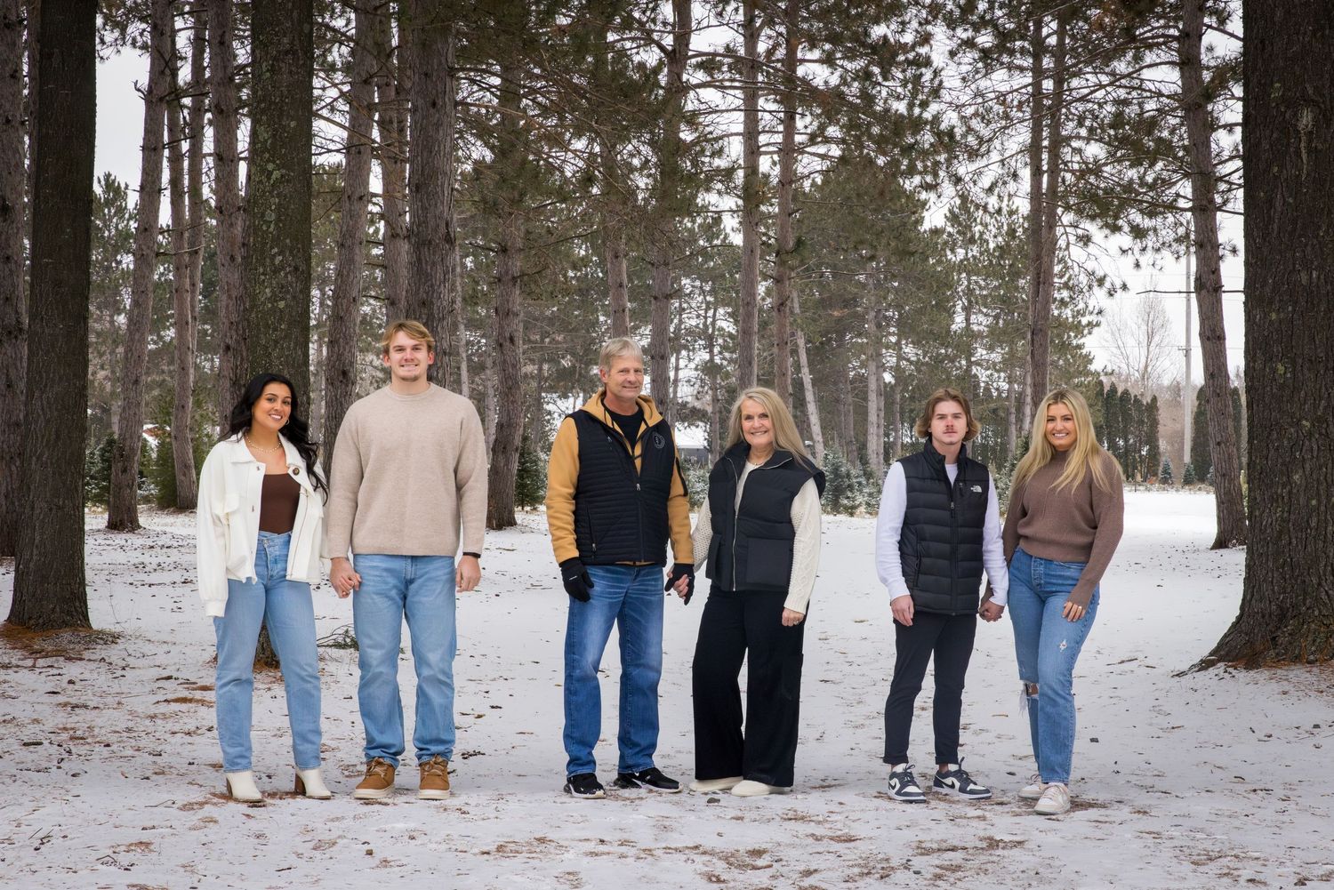 portrait of a family standing in the tree farm in winter