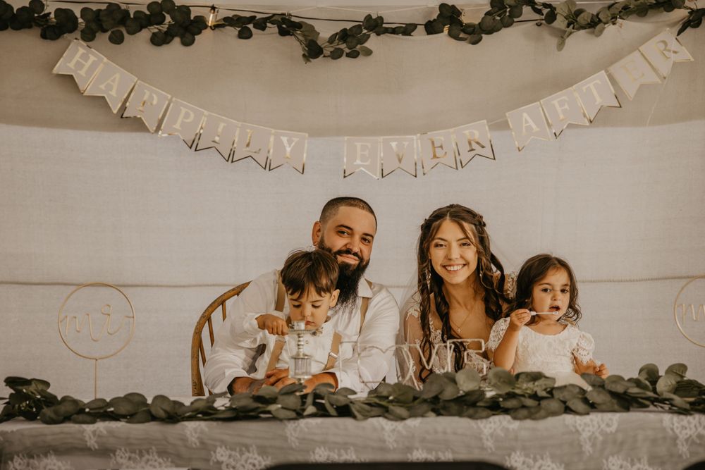Happy family of four celebrates at decorated table with Happy New Year banner and greenery garland.