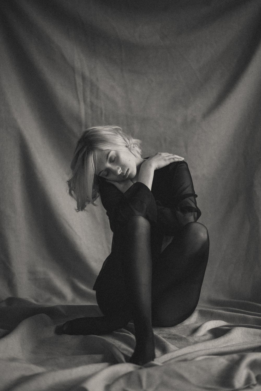 Dramatic black and white portrait on fabric backdrop with elegant pose.