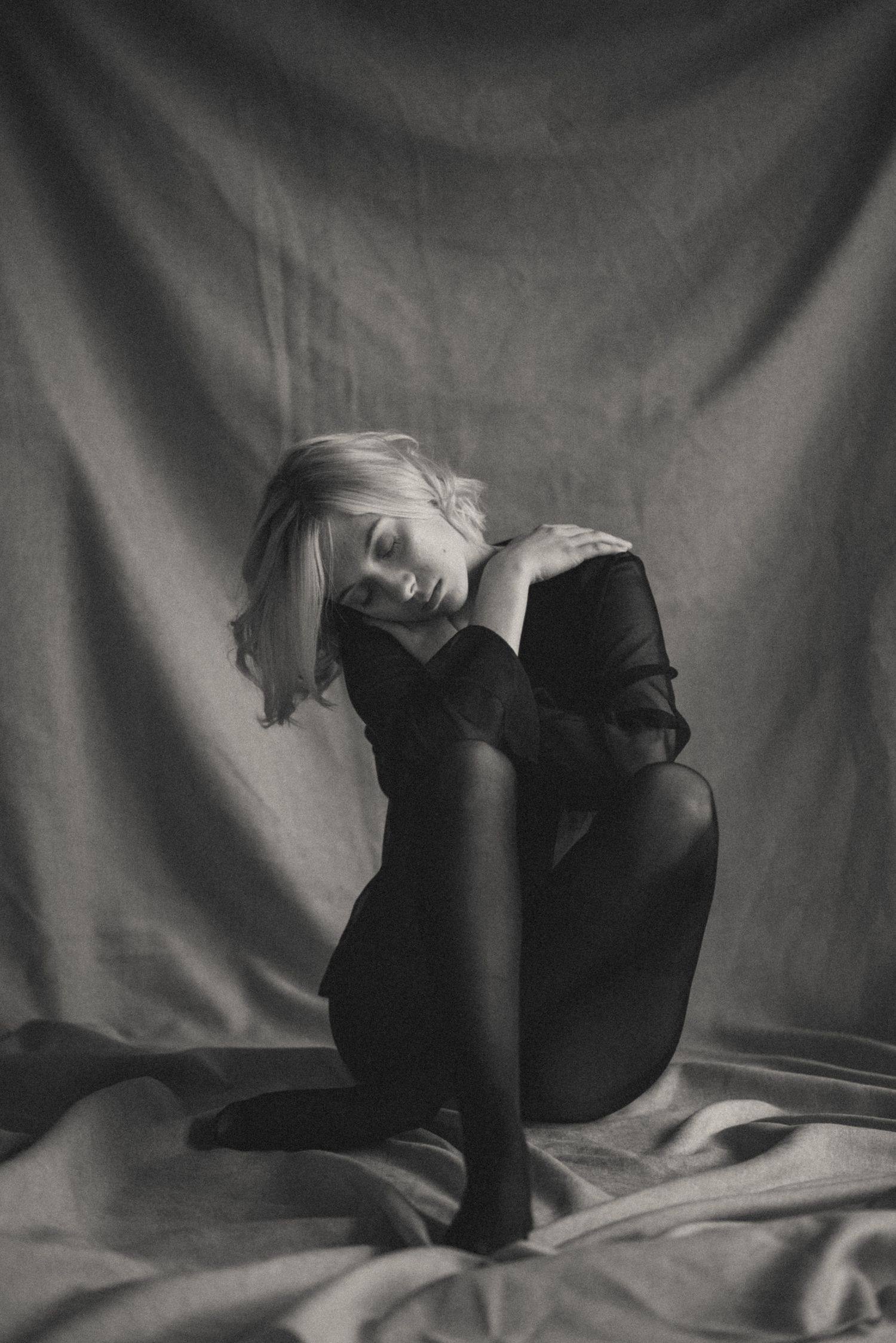Dramatic black and white portrait on fabric backdrop with elegant pose.