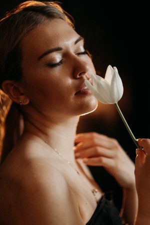 Artistic portrait series with white tulip flower against dark dramatic lighting.
