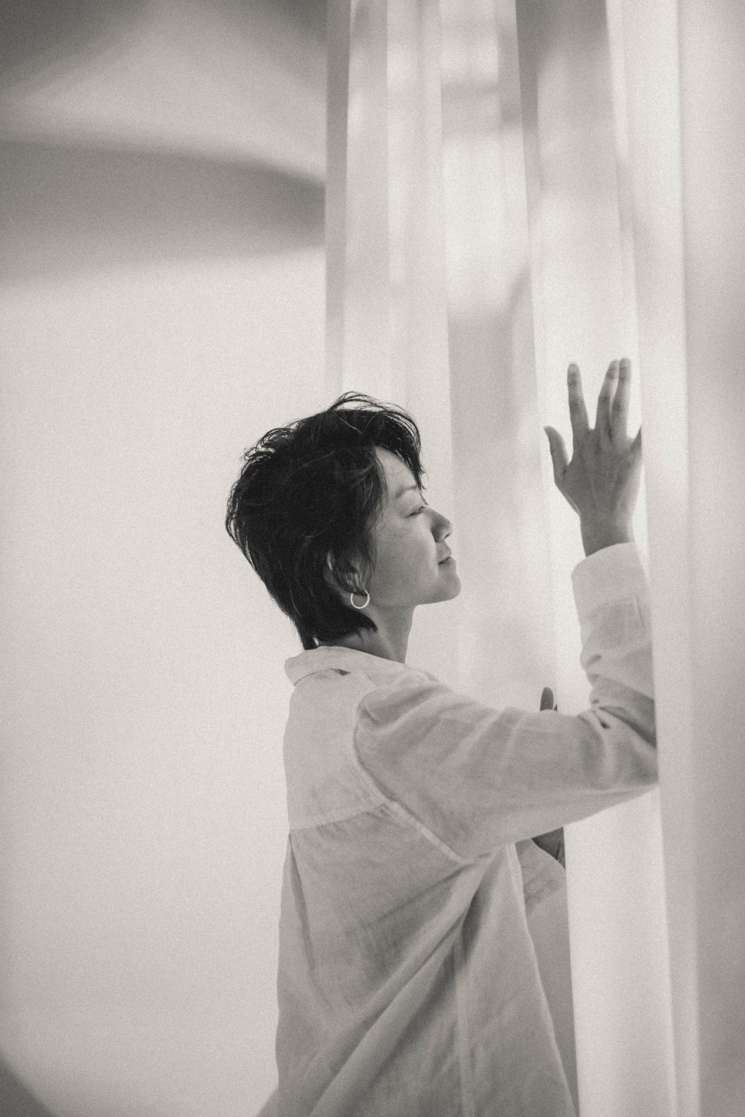 Monochrome series showing expressive movement against white curtained windows.