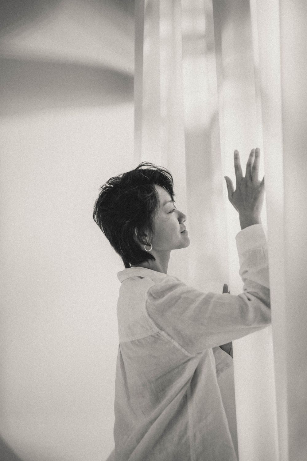 Monochrome series showing expressive movement against white curtained windows.