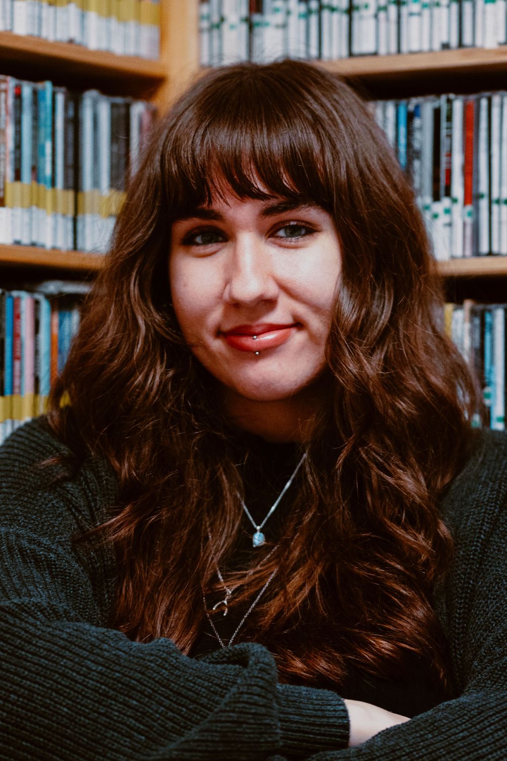 Portrait in a library with bookshelves filled with colorful books in the background.