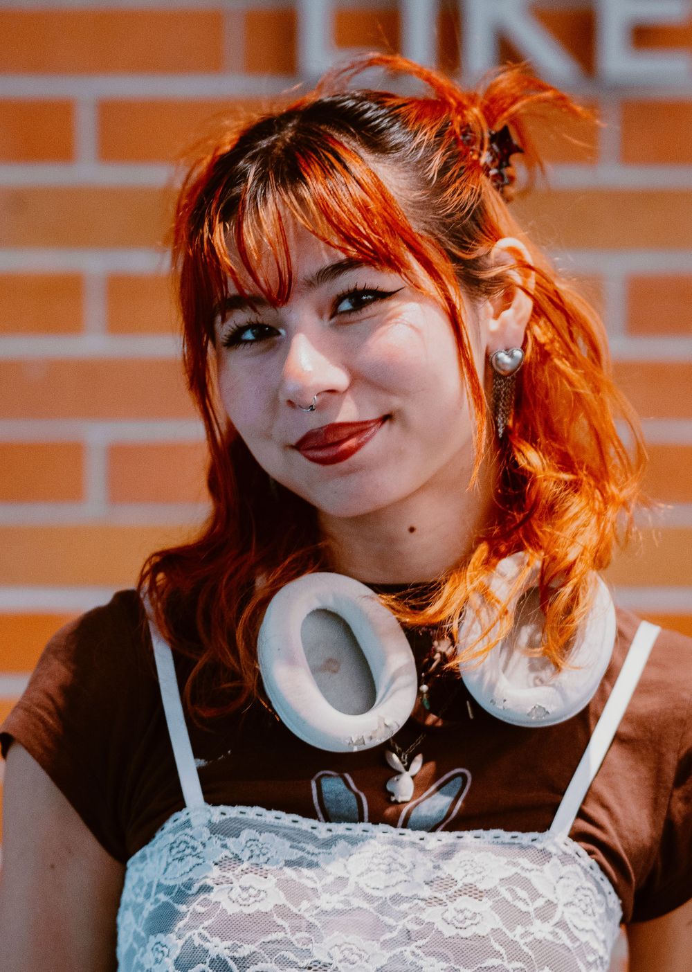 A person with vibrant red hair smiles playfully in a sequence of portrait photos against an orange wall.