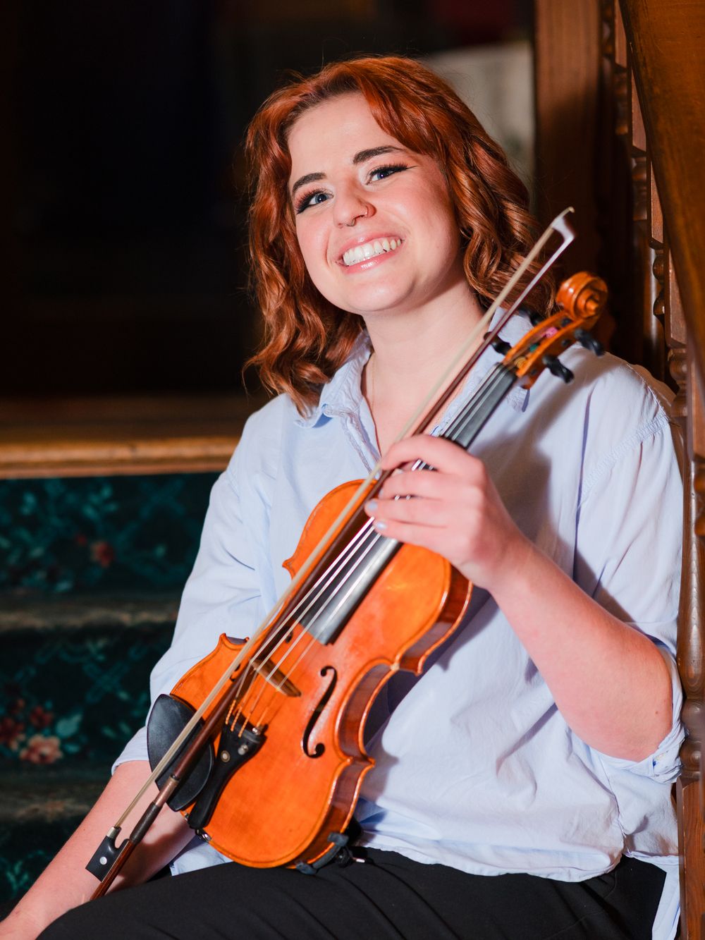 A musician holds a violin in a series of candid shots wearing a white shirt against a dark background.
