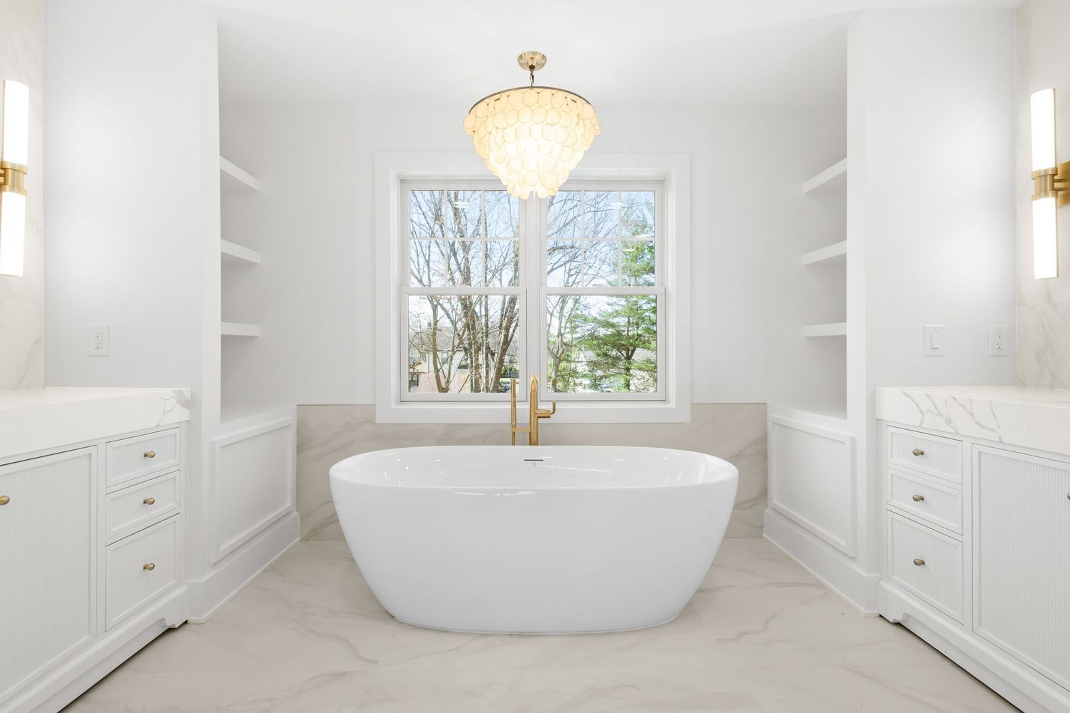 A luxurious white master bathroom with freestanding tub, built-in cabinetry, and natural light from large windows.