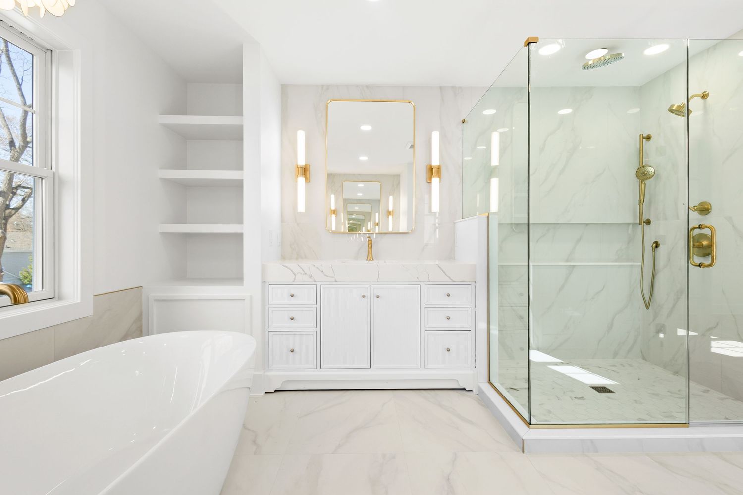 Bright modern bathroom with glass shower enclosure, shelving, and gold accents.