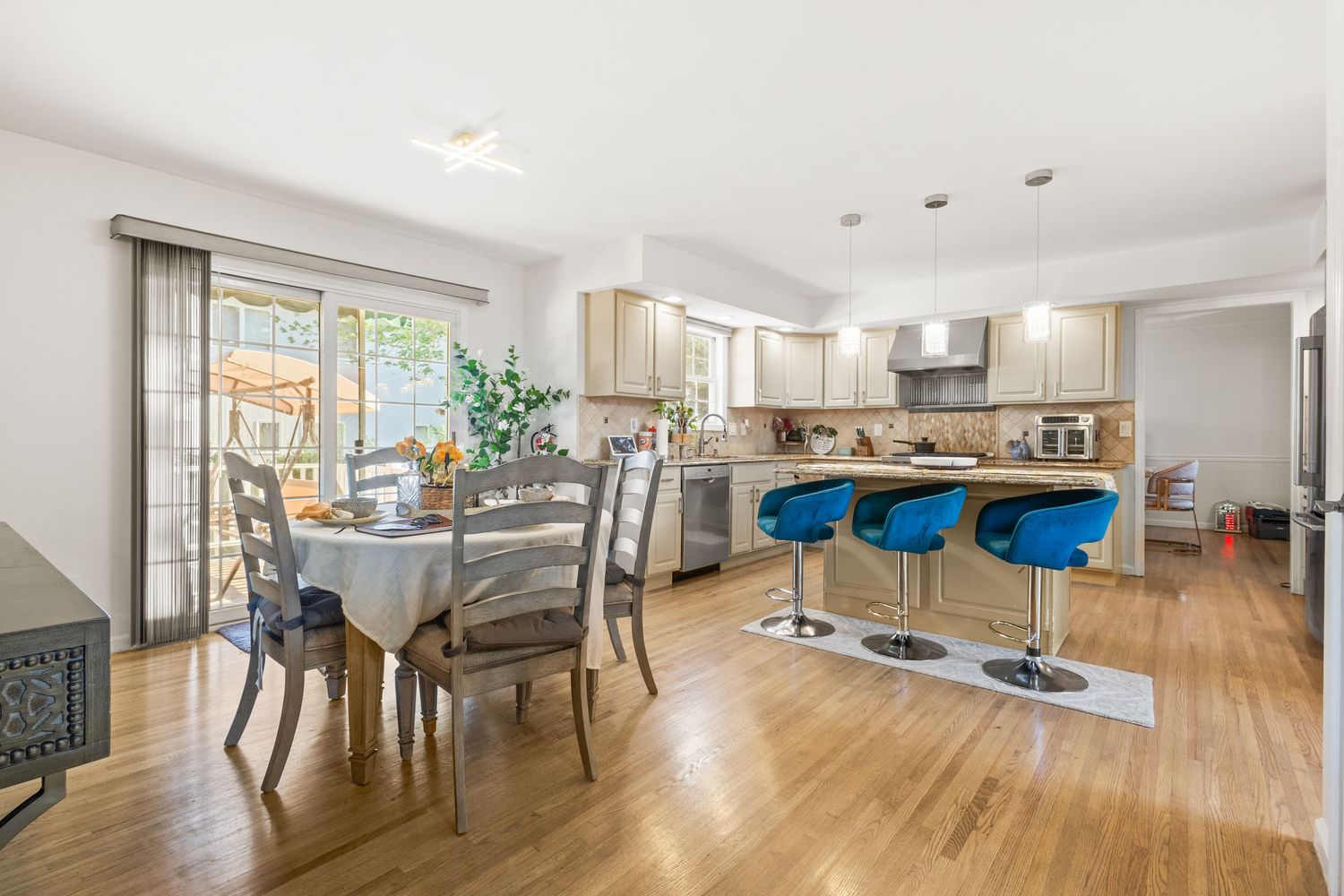 Modern open concept living area with light hardwood floors, white walls, and recessed lighting showcases a spacious layout.