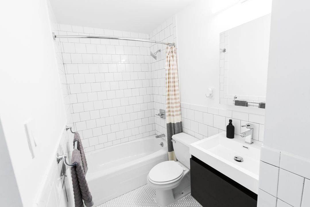 Modern white bathroom interior with subway tile, black vanity and minimal design.
