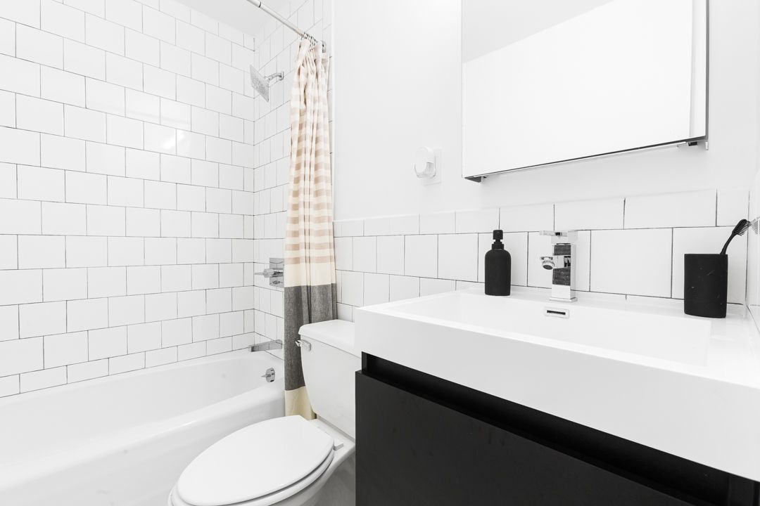 Contemporary bathroom featuring white subway tiles, black vanity, and peach striped shower curtain.