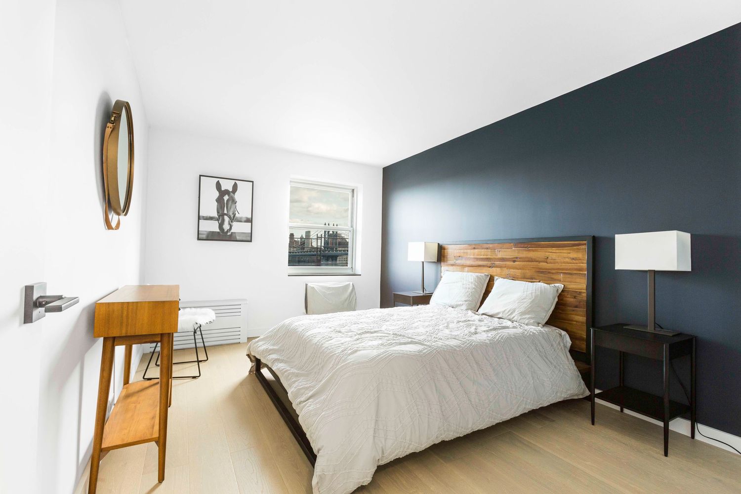 Contemporary bedroom with navy accent wall, wooden headboard, and urban artwork.