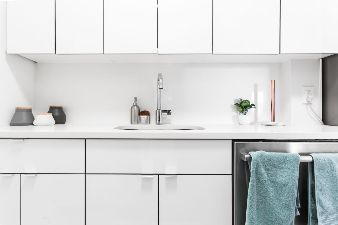 Minimalist white kitchen countertop with silver faucet and teal towel accent.