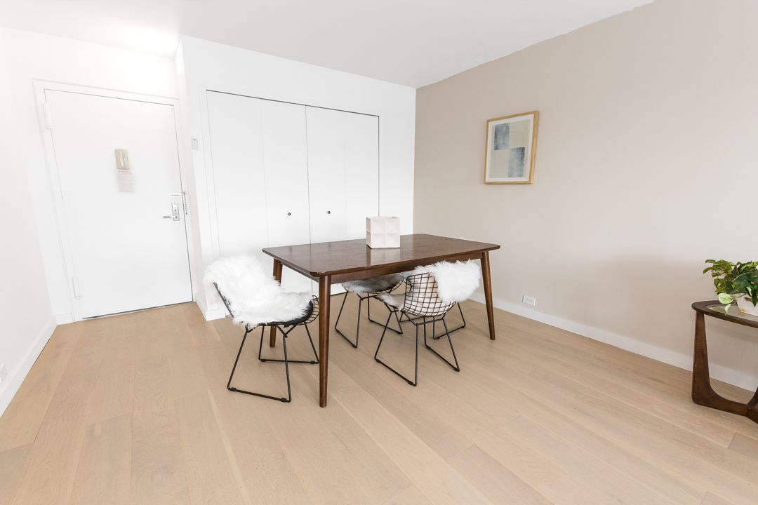 Modern dining area with white chairs, wooden table, and minimalist decor.