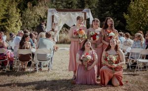 Wedding guests in colorful attire relaxing on blankets at an outdoor reception.
