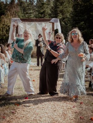 Wedding guests toss flower petals and celebrate joyfully in an outdoor garden setting.