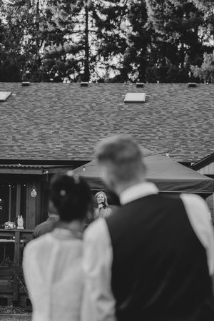 An outdoor wedding ceremony setup with guests watching a performance at a rustic venue.