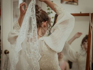 Bride in a delicate lace wedding dress twirls gracefully, showing the intricate details of her gown.