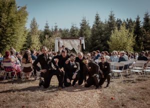 A panoramic sequence of an outdoor wedding ceremony in a rustic forest setting with guests seated on wooden benches.