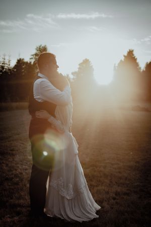 Silhouetted couple embraces in golden sunlight during their outdoor wedding photoshoot.