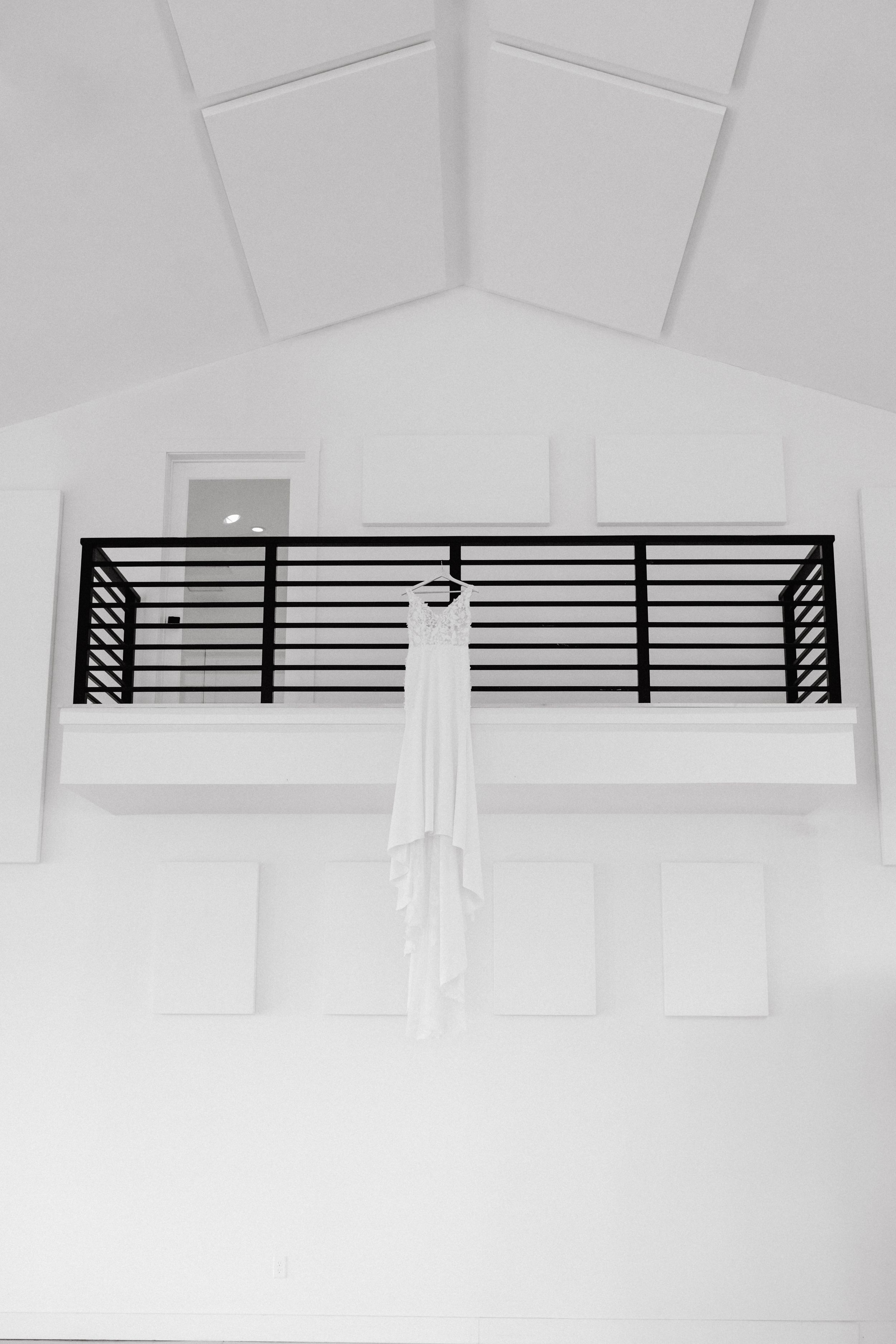 Modern black horizontal railing on a white interior balcony with vaulted ceiling and minimalist design.