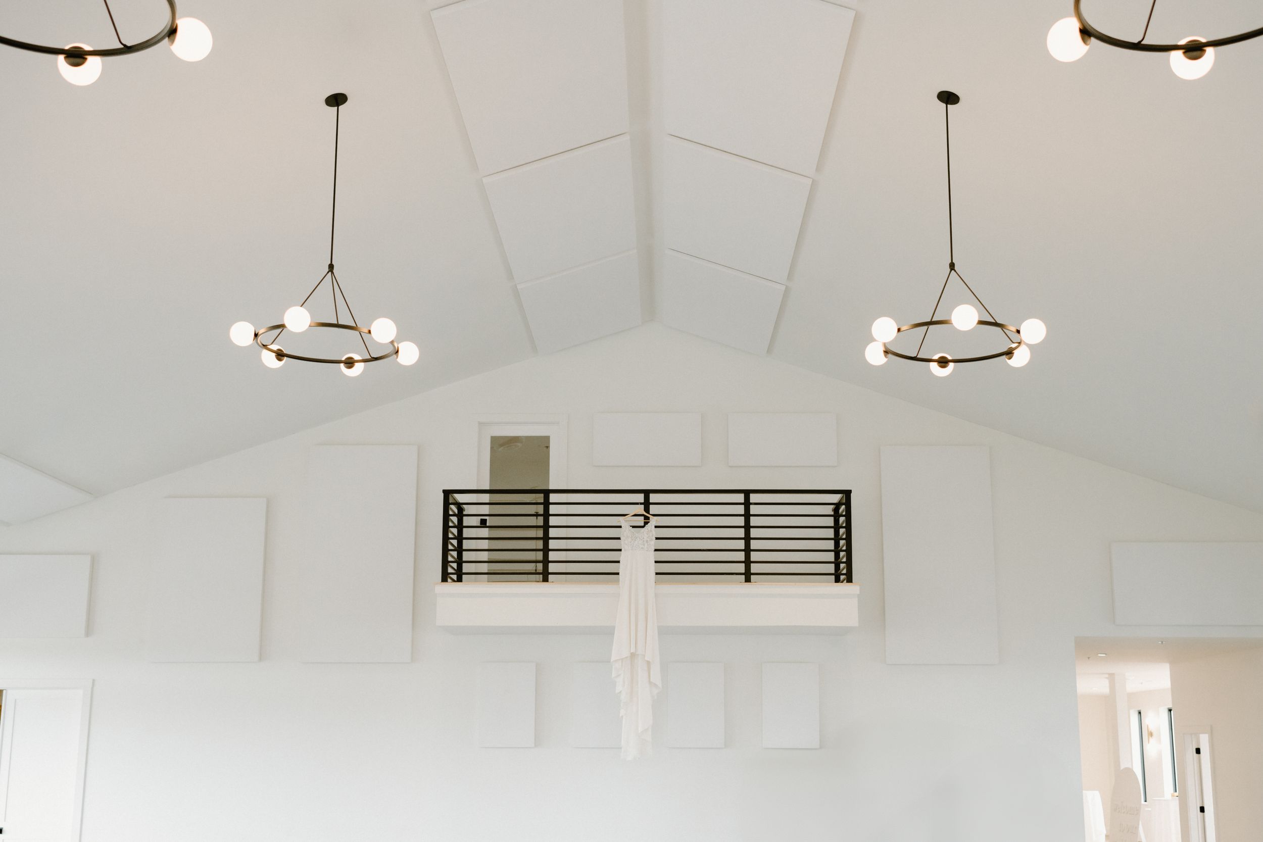 White vaulted ceiling with two modern circular pendant lights and black horizontal railing detail.