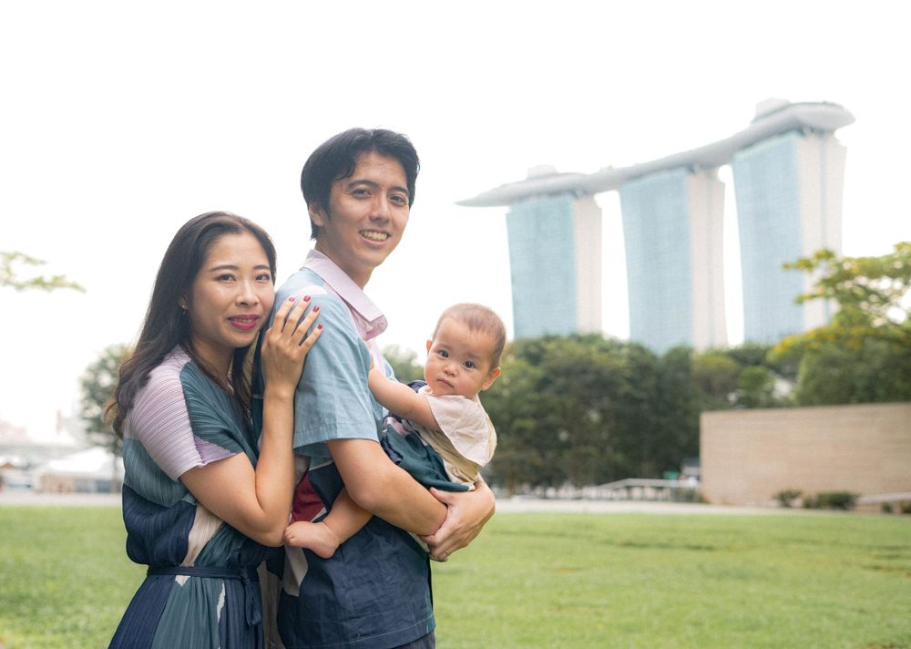A happy family poses together against Singapore's iconic Marina Bay Sands backdrop.