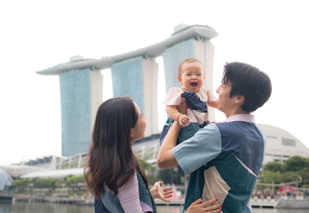 A joyful family moment captured with their baby against Singapore's skyline.