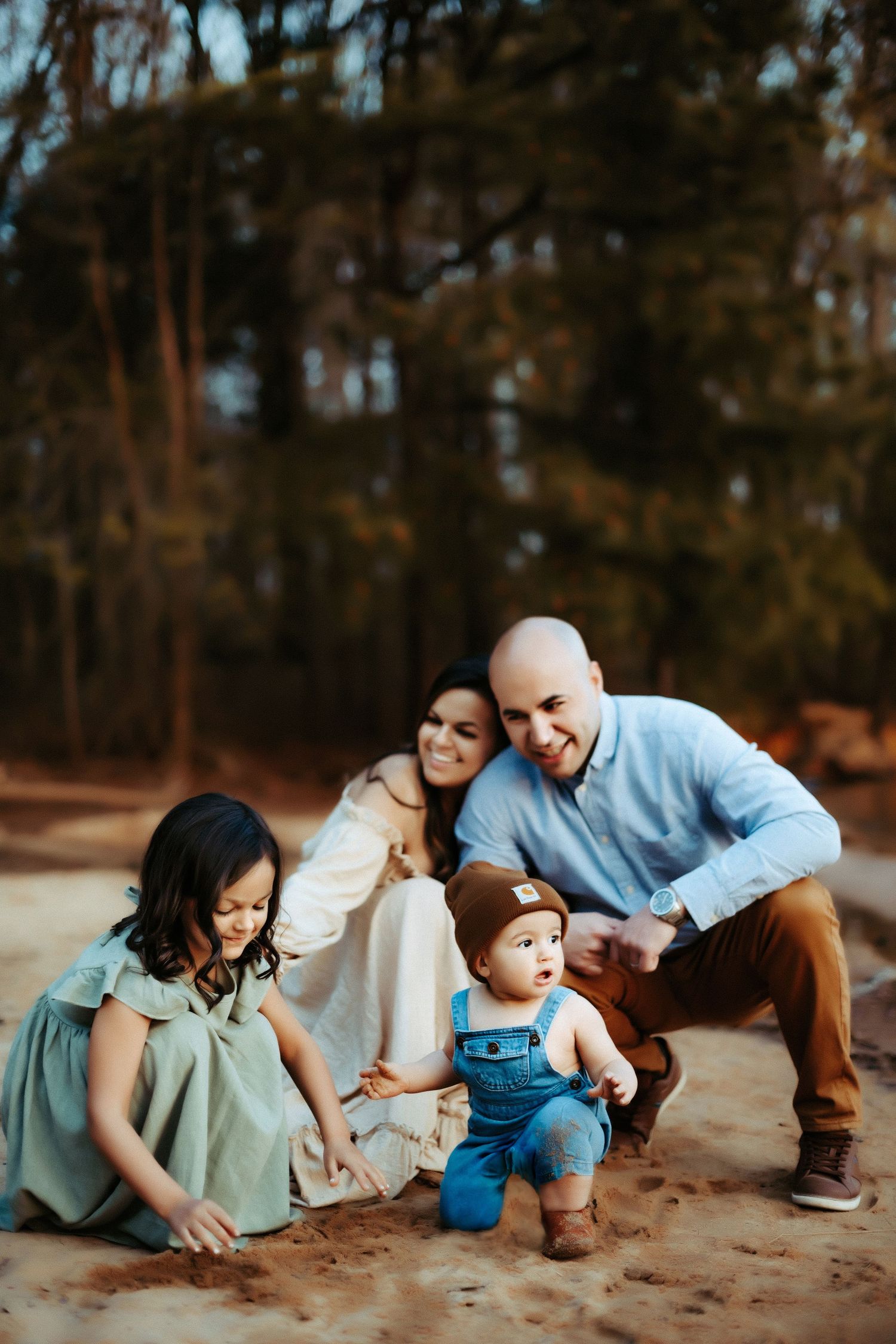 A family enjoys a playful moment together outdoors in a wooded area on a sunny afternoon.