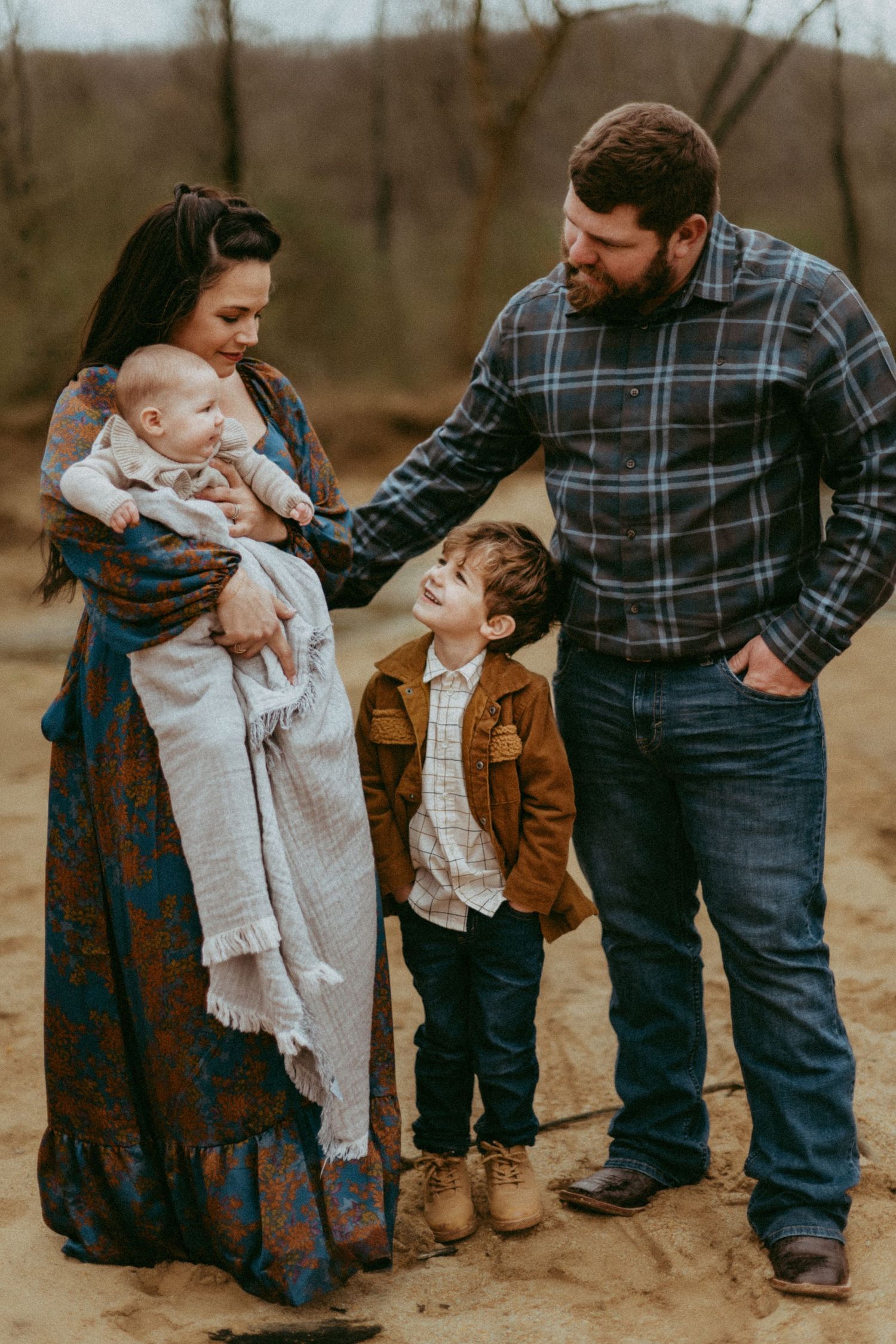 Family in casual attire standing together outdoors on a fall day in warm earth tones.