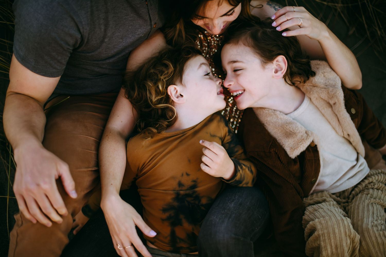Overhead view of people lying together on a wooden floor with hands intertwined.