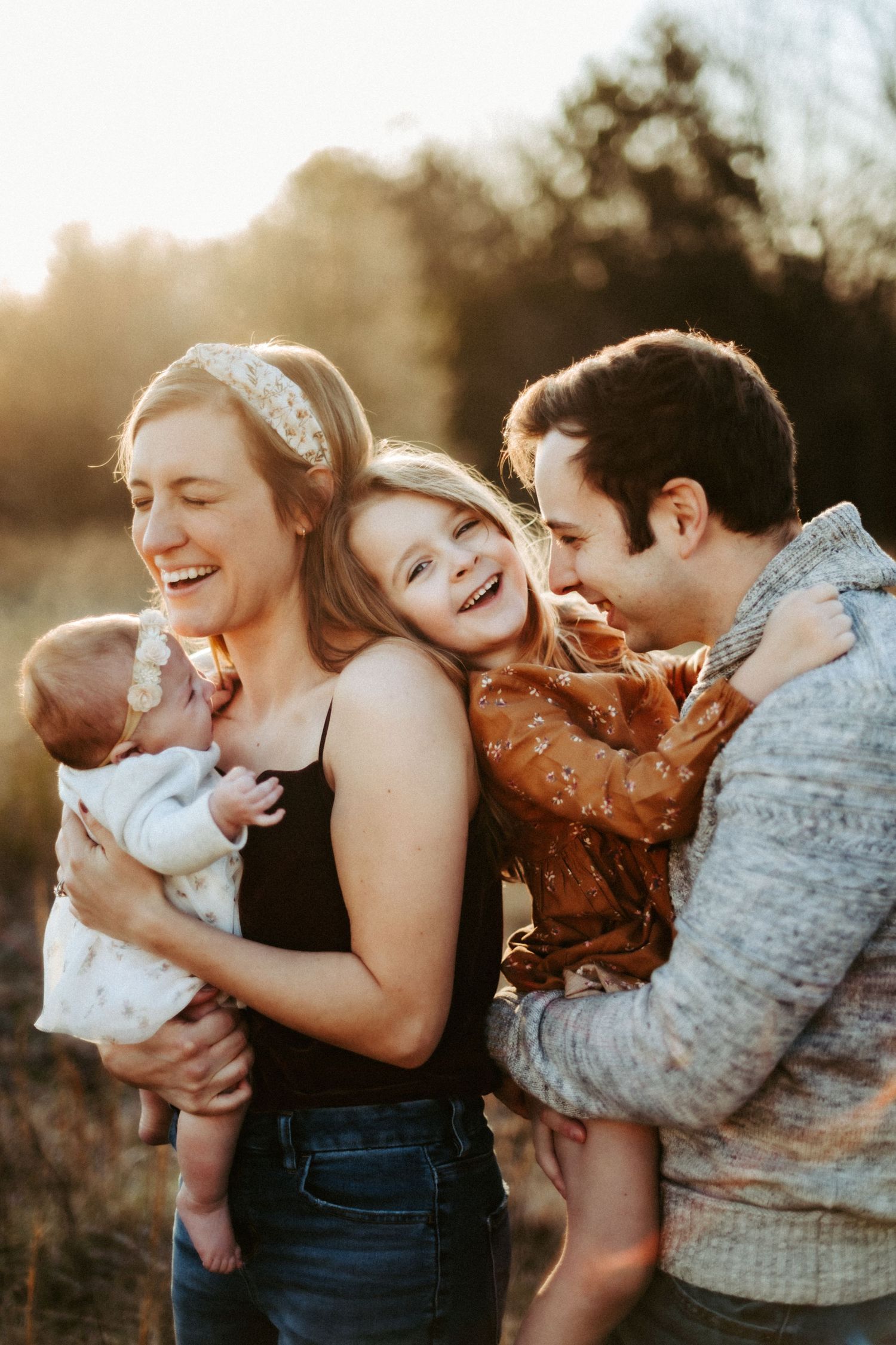 Family sharing joyful laughter together during golden hour sunset in an outdoor setting.