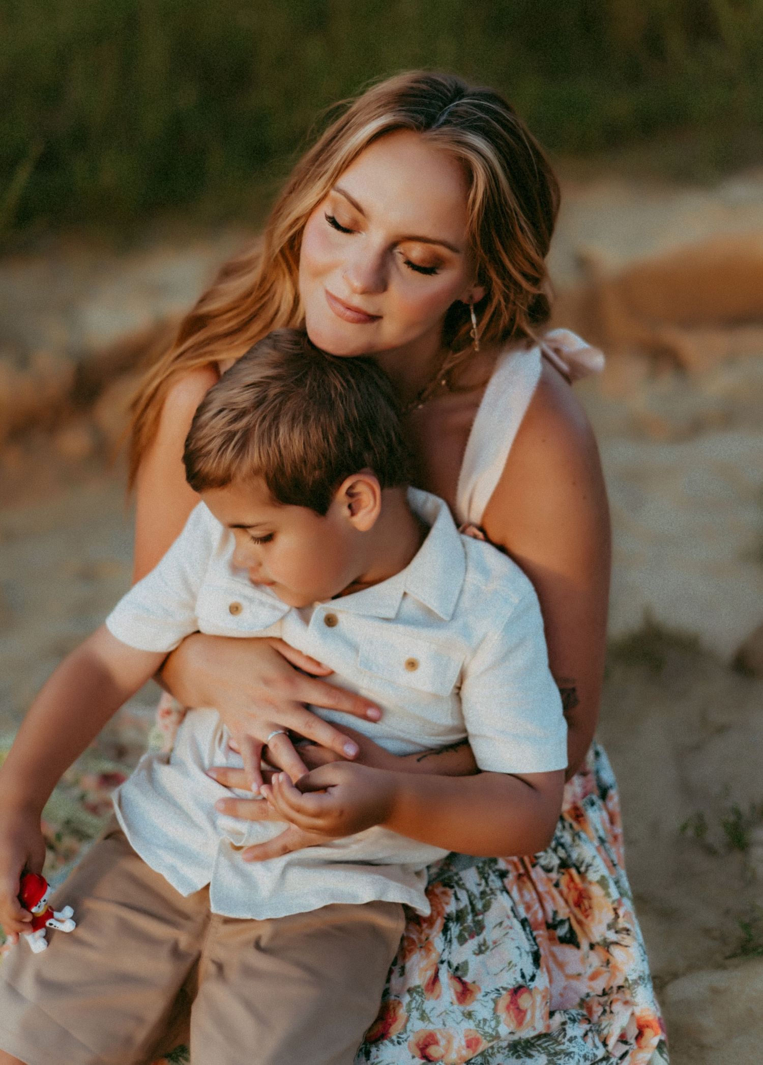 A tender embrace shared between parent and child during a warm sunset photoshoot on the beach.