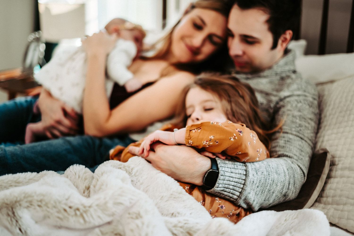 Family shares intimate moment while resting together under cozy blankets.