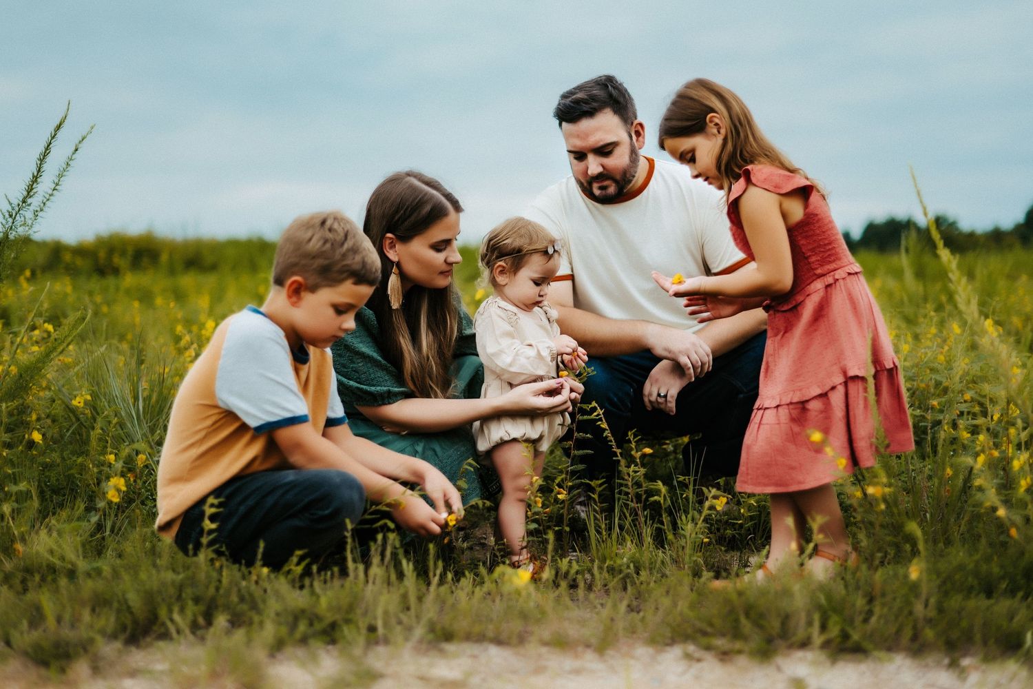 A group gathers together in a sunny meadow with tall grass and wildflowers on a bright summer day.