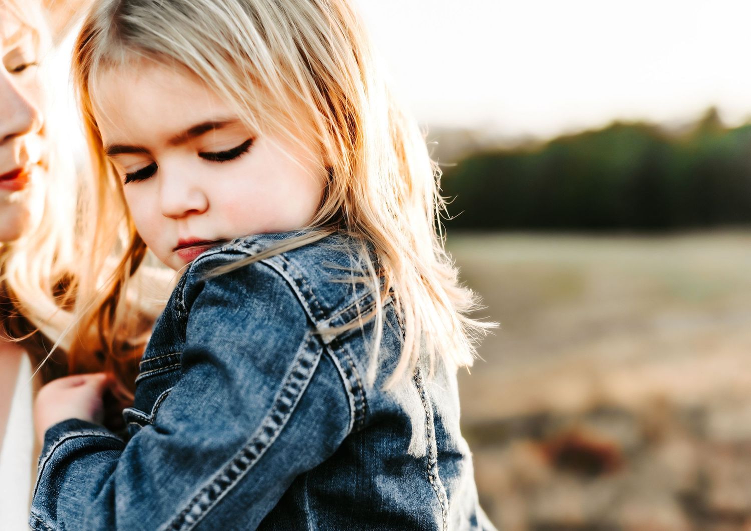 Sunlit close-up portrait of someone wearing a denim jacket in soft golden light at sunset.