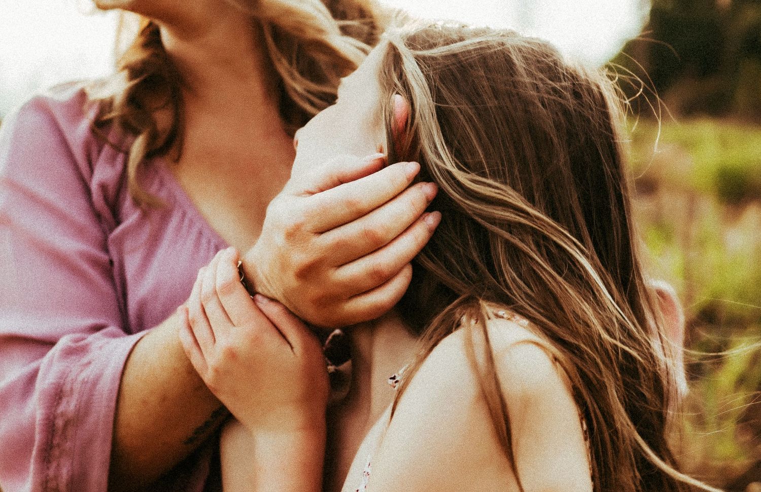 A tender moment captured in warm sunlight as someone comforts another with a gentle hand on their face.