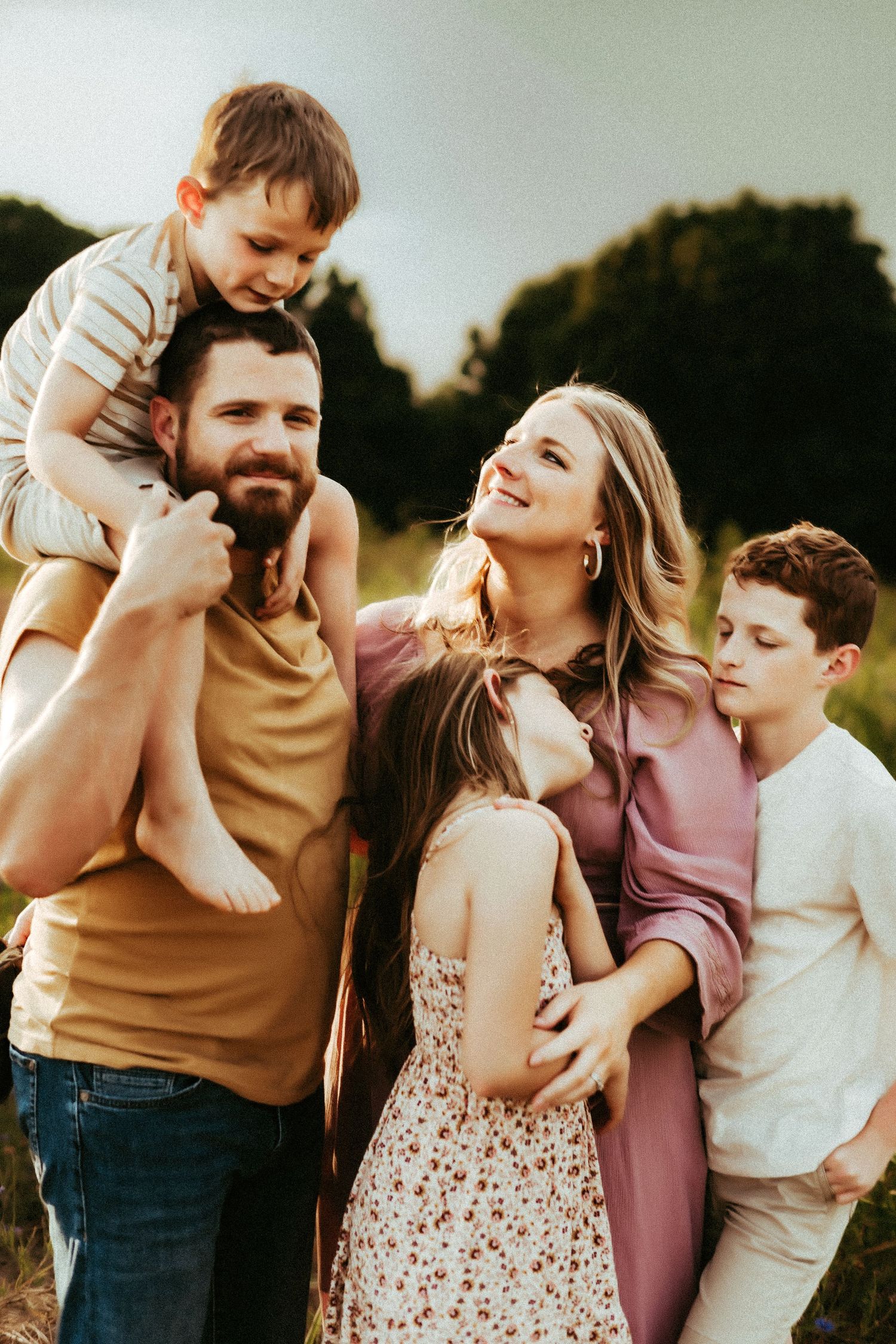 Happy family enjoying a warm sunset moment together outdoors in casual clothing.