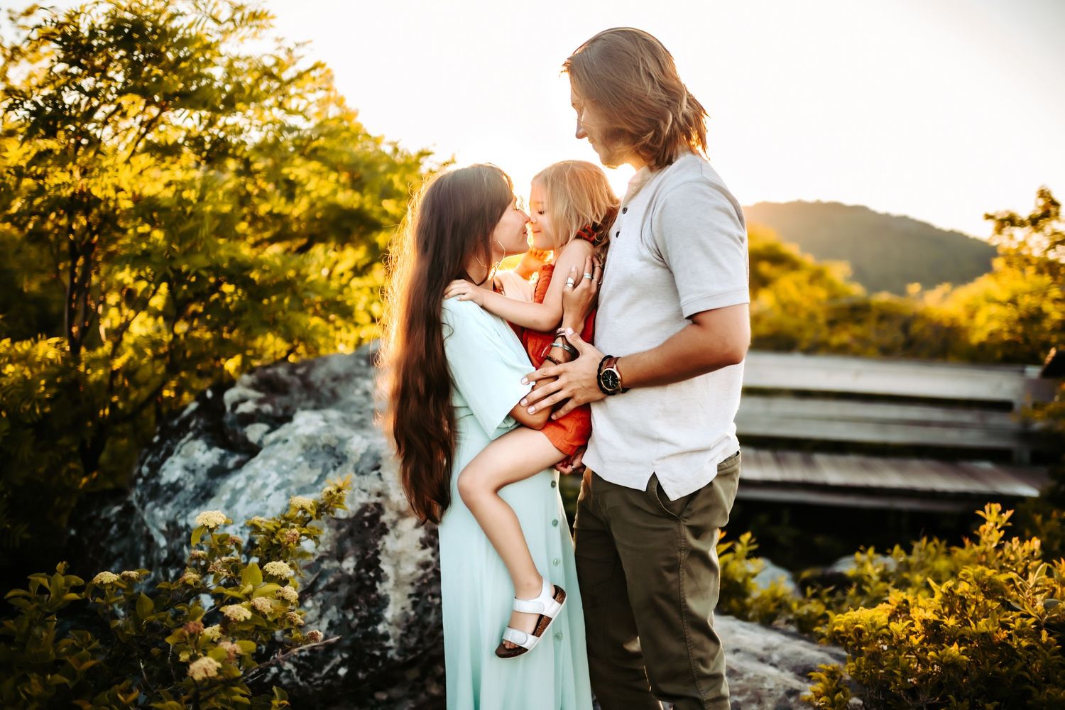 A loving family shares a tender moment together at sunset in a beautiful outdoor mountain setting.