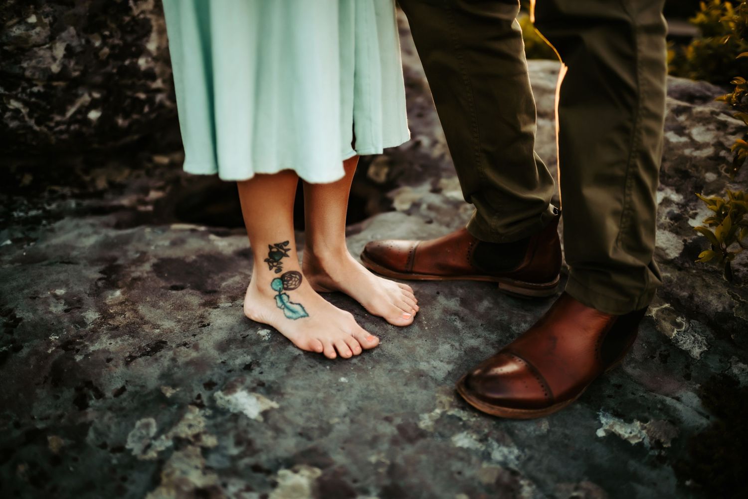 Intimate detail shot showing contrasting footwear between two people standing on stone surface.