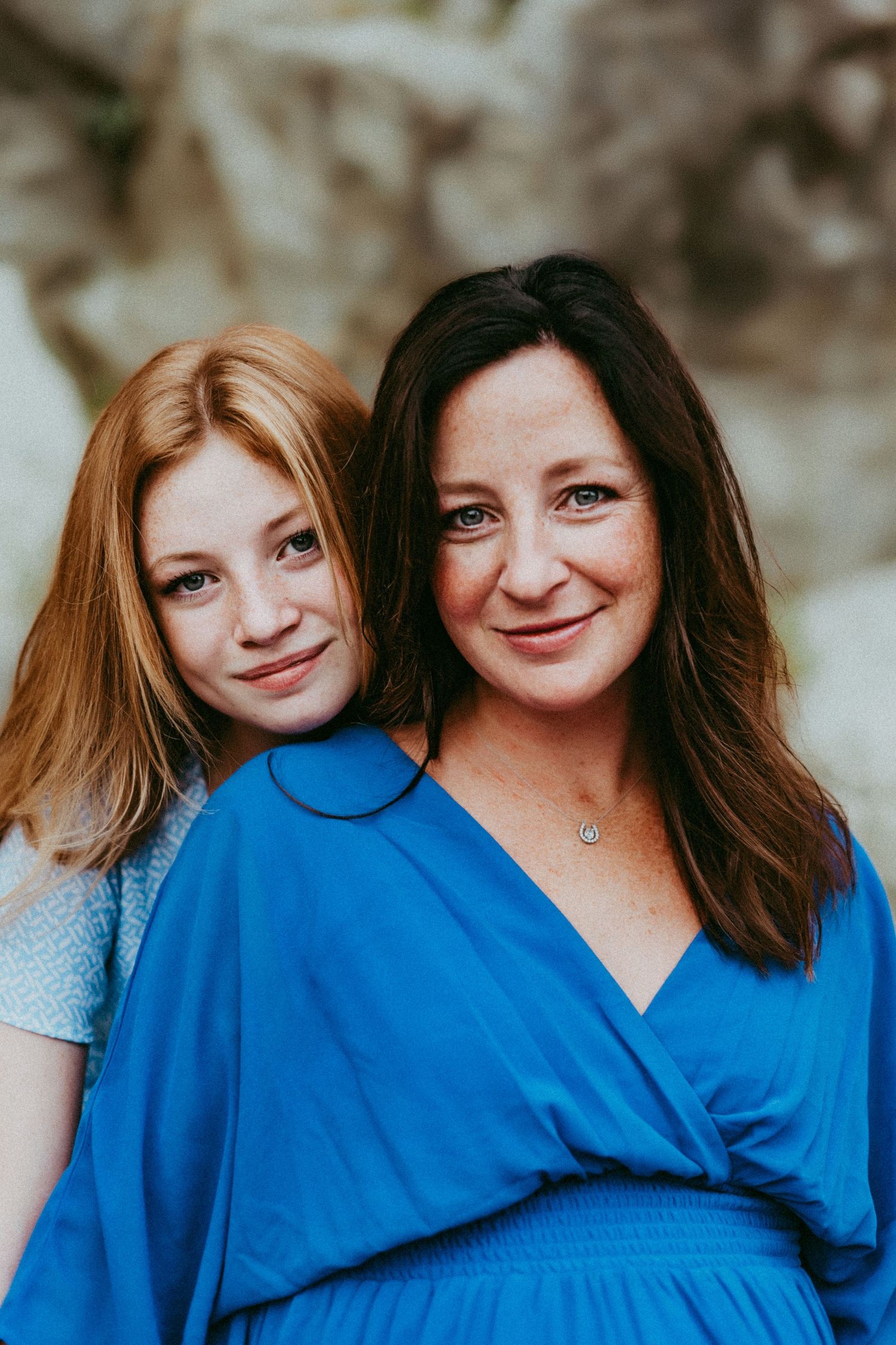 Two people wearing matching blue outfits pose together for a heartwarming portrait outdoors.