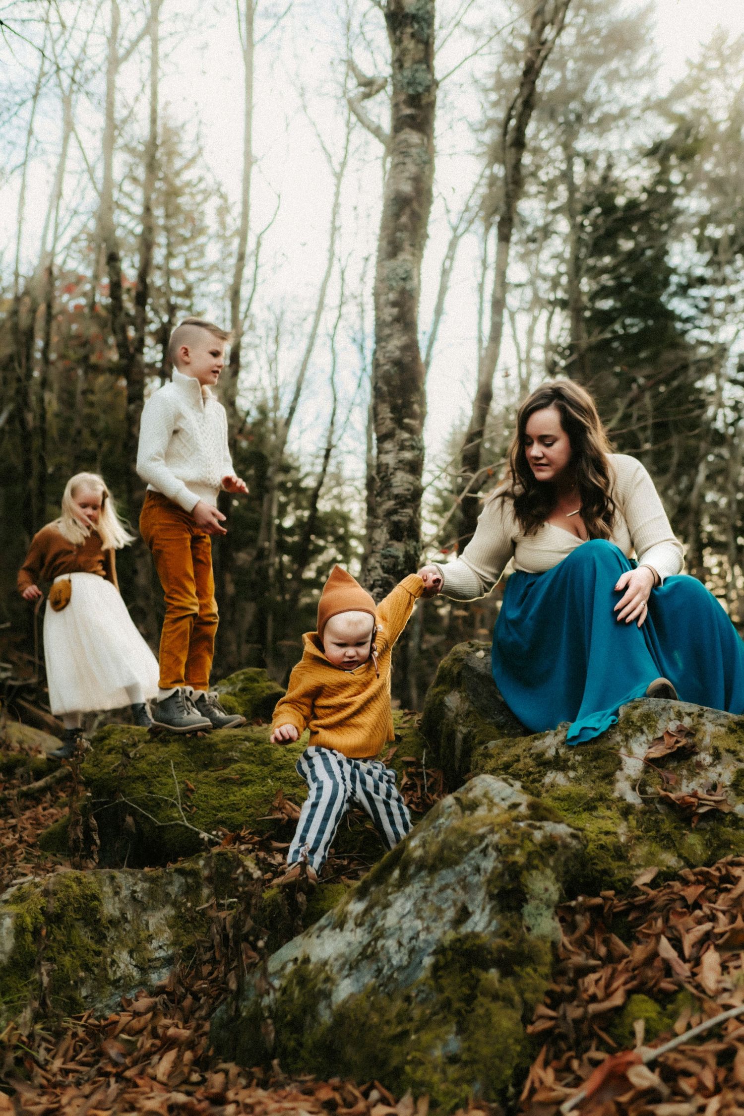 A group exploring together on moss-covered rocks in a misty forest during autumn.