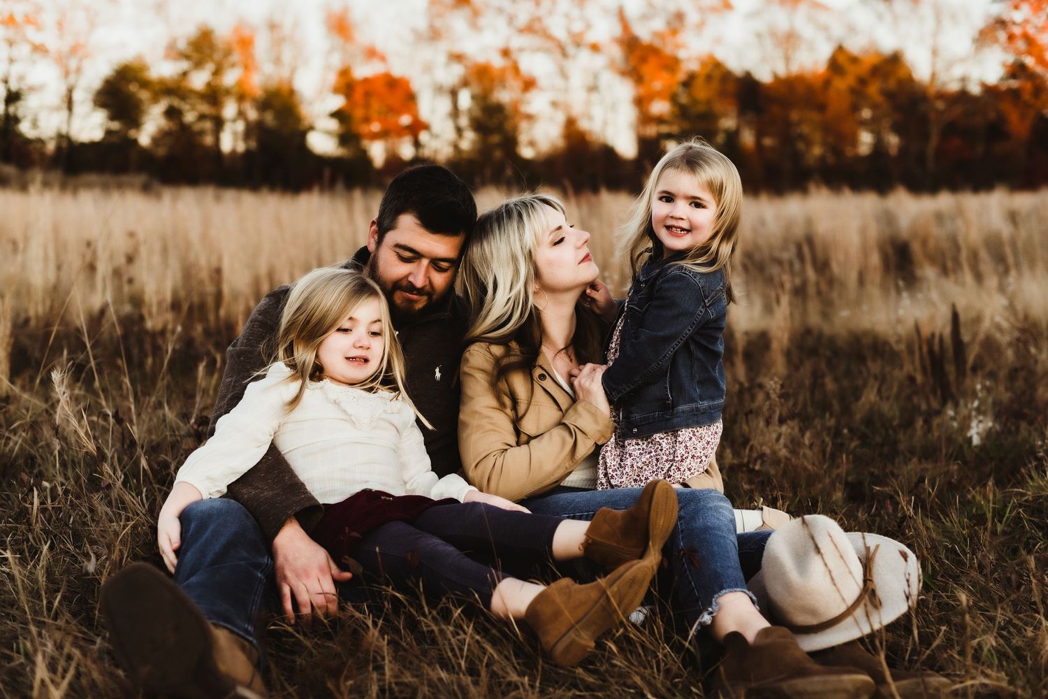A group sits together enjoying a warm autumn day in a golden field during sunset.