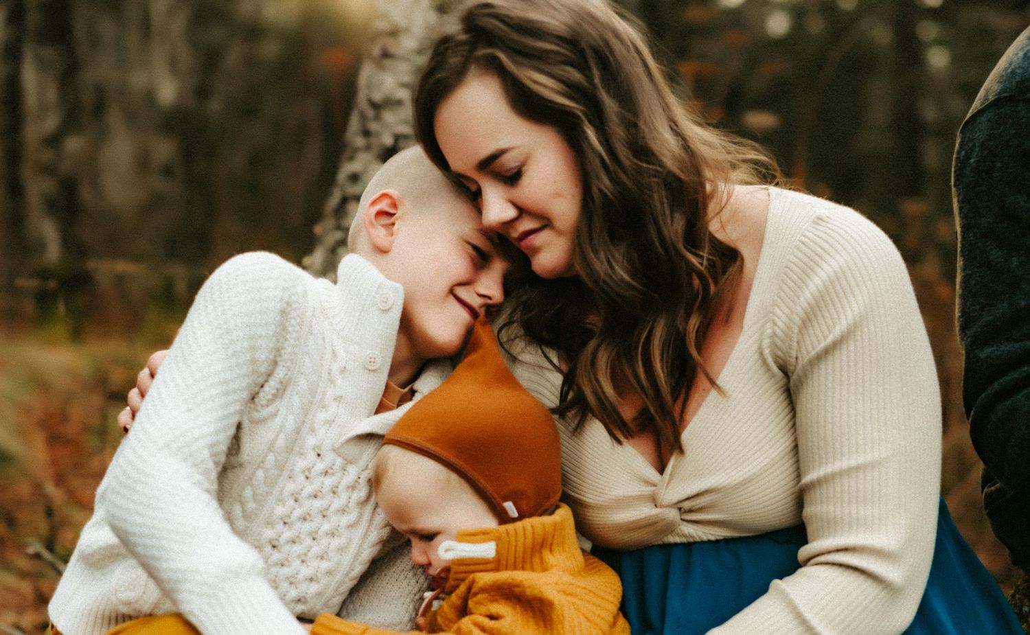 A tender heartwarming moment between two figures wearing white knit sweaters sharing laughter outdoors.