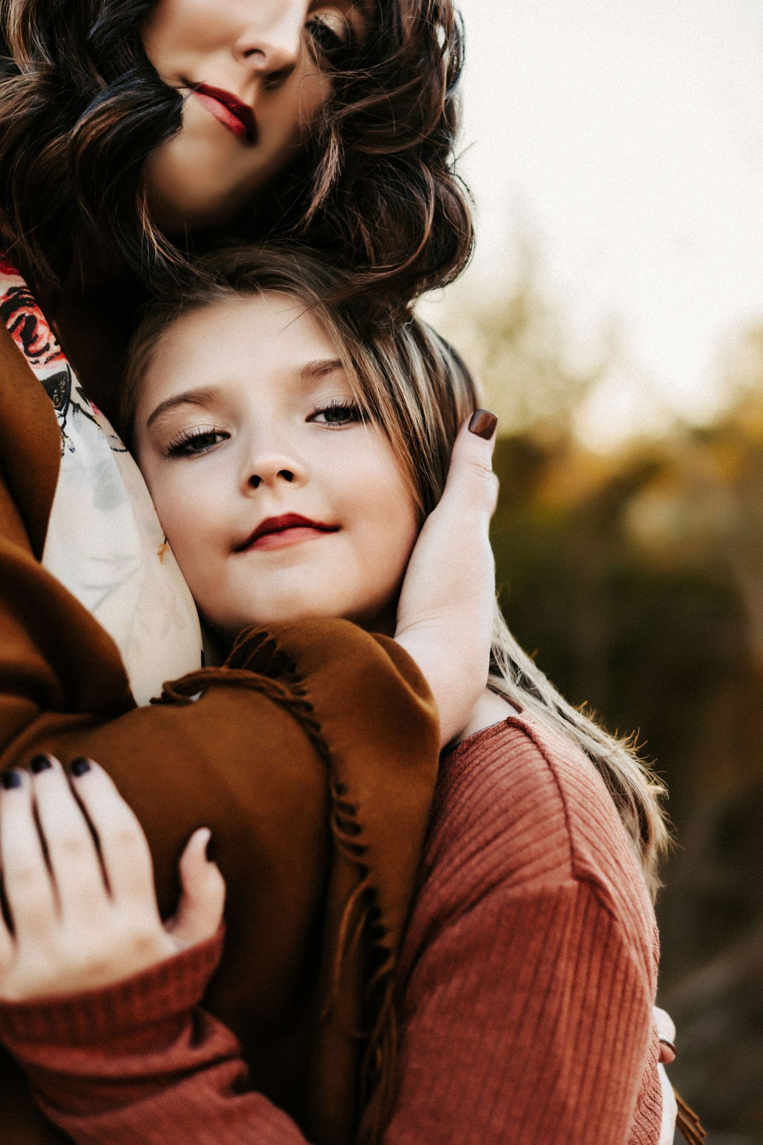 Close-up portrait in warm tones showing an intimate embrace with soft natural lighting and autumn colors in background.