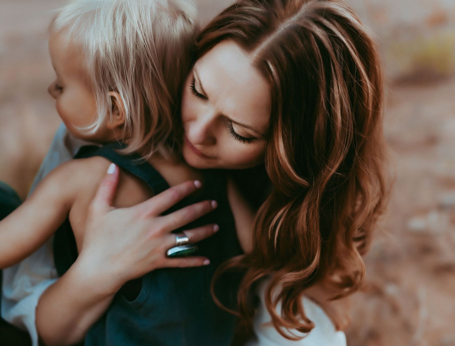 A tender moment captured between mother and child embracing outdoors with soft lighting and warm tones.