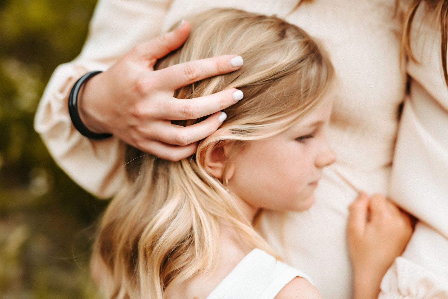 A close-up shot shows gentle hands stroking blonde hair against a soft blurred background.